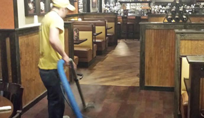 Worker vacuuming restaurant floor