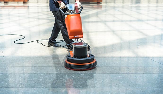 worker cleaning floor with industrial floor cleaner