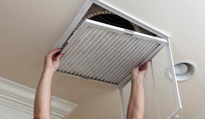 person cleaning air filter of a ceiling vent